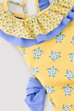 Bañador niña detalles volantes y lazos estampado tortugas amarillo
