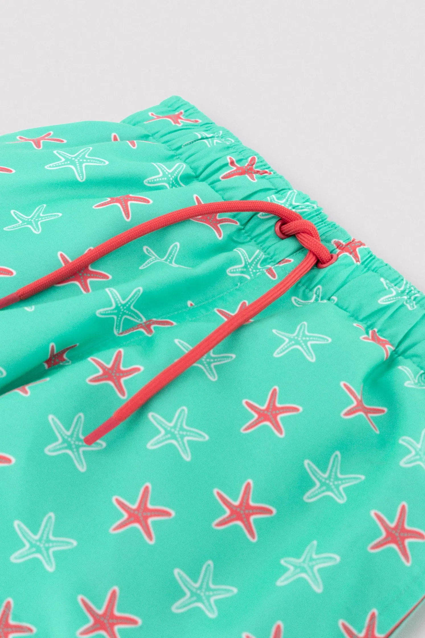 Bañador niño corto estampado estrellas marinas turquesa